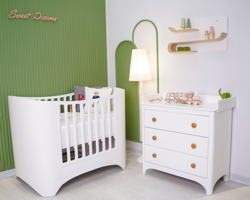 تخت نوزاد مدرن سوییت با دراور و میز تعویض کودک سفید، با پسزمینه دیواری سبز رنگ