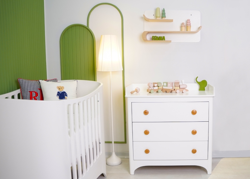 نمای نزدیک از دراور سه کشوی سوییت با دستگیرههای چوبی و تخت نوزاد با طراحی مدرن و منحنی