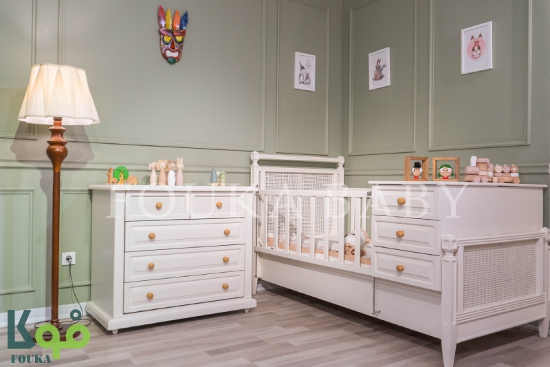 تخت دو منظوره نوزاد و دراور کنار آن از سرویس آیریس به رنگ کرم با بافت حصیری در اتاق سبز روشن