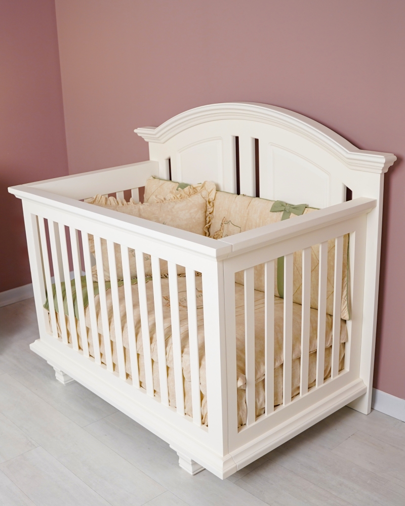 نمای نزدیک از تخت نوزاد چوبی روژان به رنگ سفید با جزئیات کلاسیک و طراحی محافظ