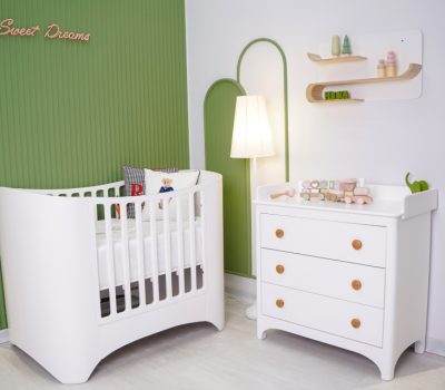 تخت نوزاد مدرن سوییت با دراور و میز تعویض کودک سفید، با پس‌زمینه دیواری سبز رنگ