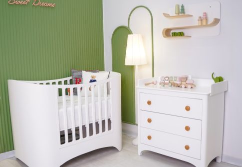 تخت نوزاد مدرن سوییت با دراور و میز تعویض کودک سفید، با پس‌زمینه دیواری سبز رنگ